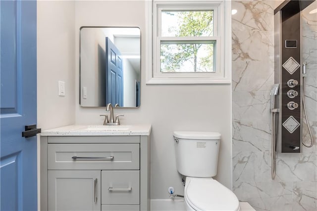 bathroom featuring tiled shower, vanity, and toilet