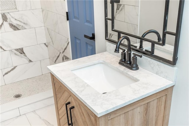 bathroom featuring tiled shower and vanity