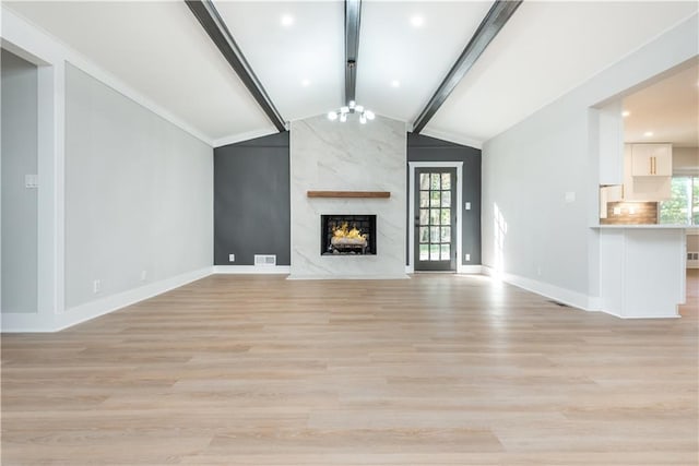 unfurnished living room with lofted ceiling with beams, light hardwood / wood-style flooring, a notable chandelier, and a premium fireplace