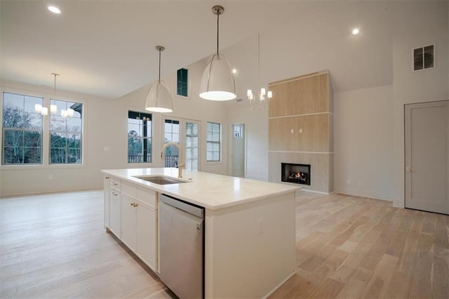 kitchen with stainless steel dishwasher, an inviting chandelier, high vaulted ceiling, visible vents, and a sink