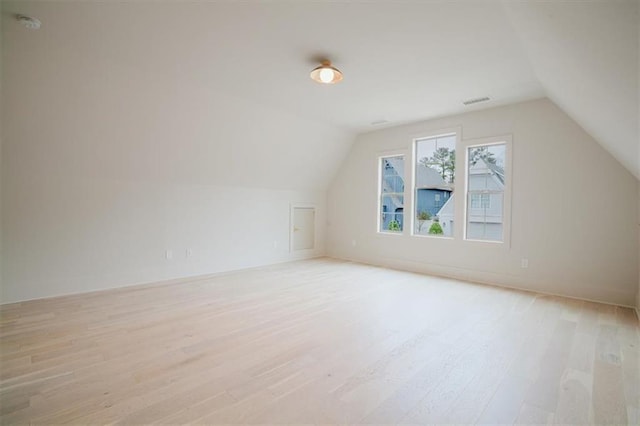 additional living space featuring visible vents, vaulted ceiling, and light wood-style floors