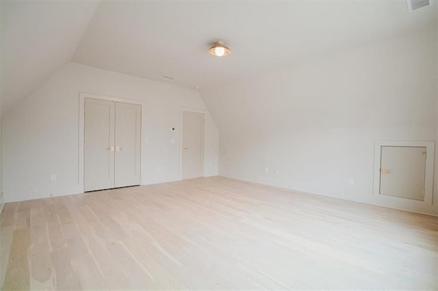 additional living space featuring visible vents, light wood finished floors, and lofted ceiling