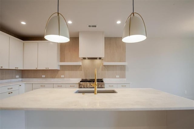 kitchen with recessed lighting, an island with sink, light stone countertops, visible vents, and a sink