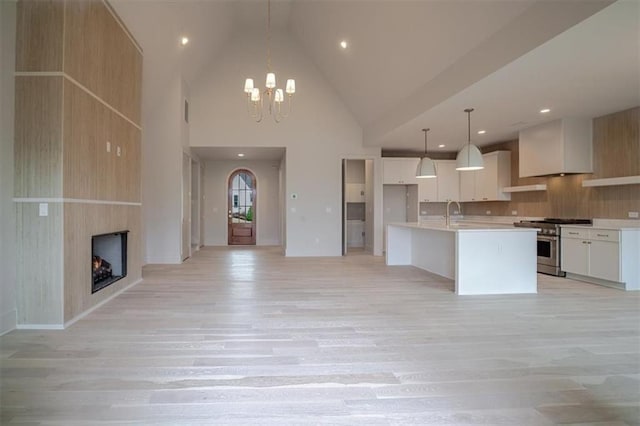 kitchen with open floor plan, light countertops, decorative light fixtures, high end stainless steel range, and light wood finished floors