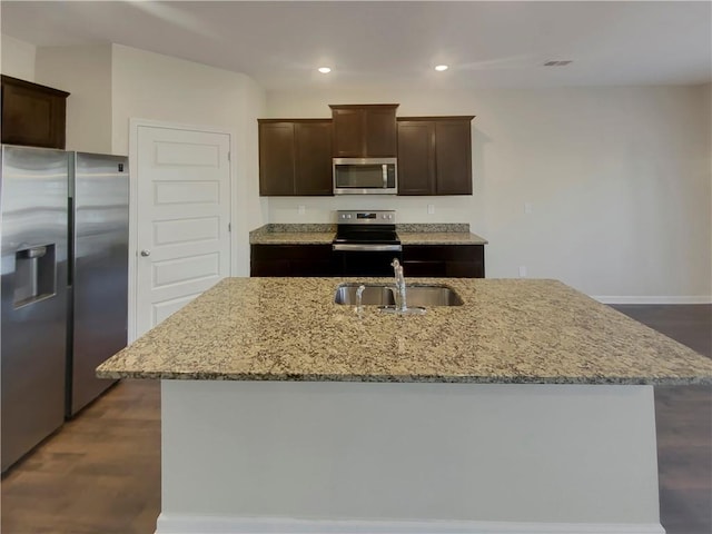 kitchen featuring dark brown cabinetry, appliances with stainless steel finishes, light stone countertops, a sink, and recessed lighting