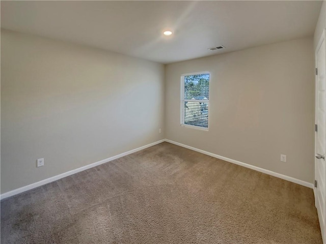 empty room featuring carpet, visible vents, and baseboards