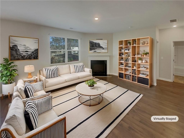 living area featuring recessed lighting, visible vents, a fireplace with flush hearth, wood finished floors, and baseboards