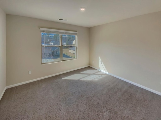 carpeted spare room featuring visible vents and baseboards