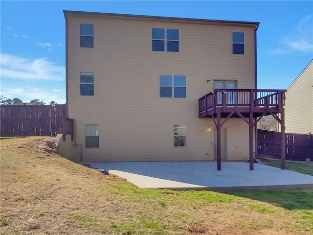 rear view of property featuring a patio, a lawn, a wooden deck, and fence