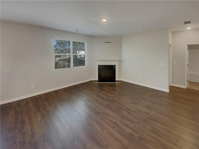 unfurnished living room with visible vents, dark wood finished floors, baseboards, a fireplace with flush hearth, and recessed lighting