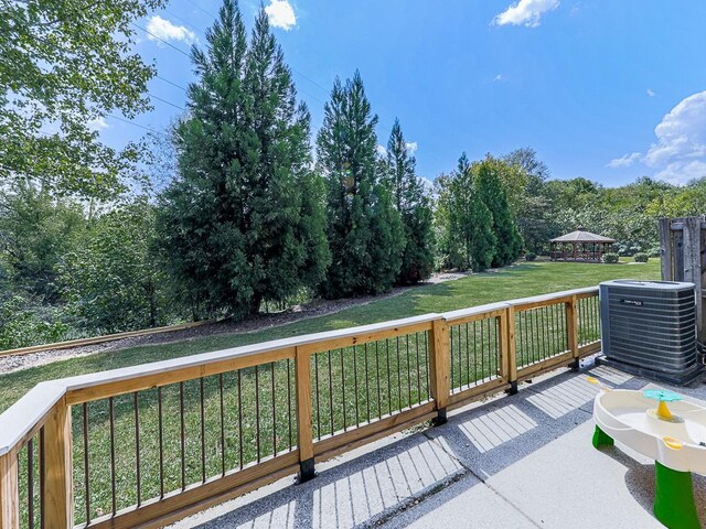 deck featuring cooling unit, a gazebo, and a lawn