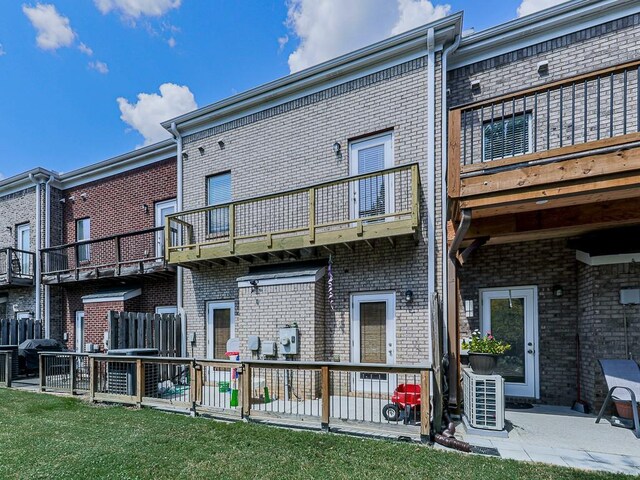 back of house with cooling unit, a balcony, and a yard