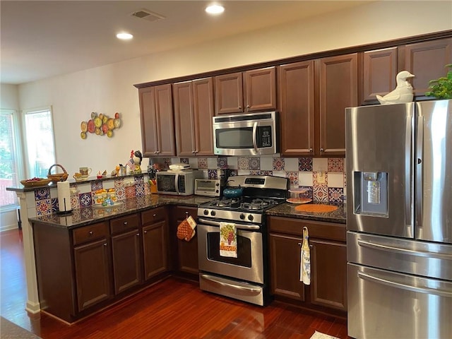 3692 Archgate Ct, Alpharetta, GA 30004 - kitchen featuring stainless steel appliances, a peninsula, dark wood-style floors, dark stone counters, and recessed lighting