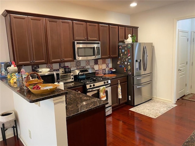 3692 Archgate Ct, Alpharetta, GA 30004 - kitchen with appliances with stainless steel finishes, dark wood-type flooring, dark stone counters, a peninsula, and recessed lighting