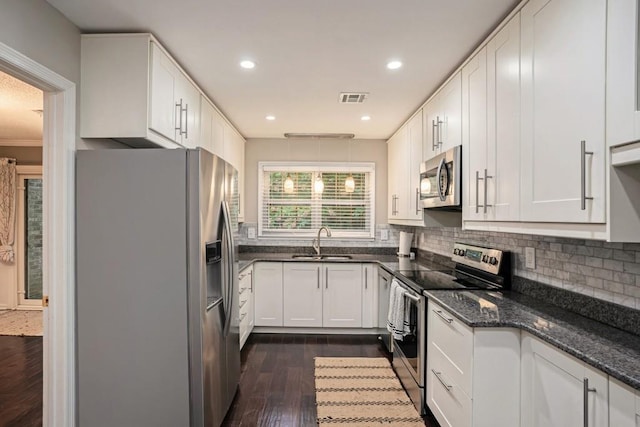 kitchen with sink, dark hardwood / wood-style floors, dark stone counters, white cabinets, and appliances with stainless steel finishes