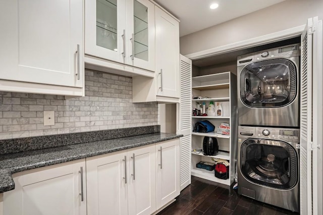 clothes washing area with dark wood-type flooring and stacked washer / drying machine