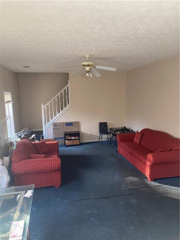 carpeted living room with ceiling fan and a textured ceiling