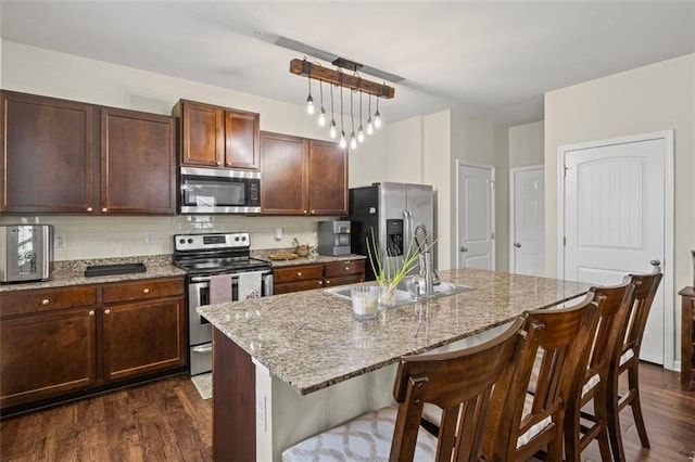 8553 Braylen Manor Dr, Douglasville, GA 30134 - kitchen with appliances with stainless steel finishes, dark wood-type flooring, a kitchen bar, and decorative backsplash