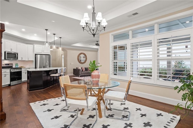 dining space featuring ceiling fan with notable chandelier, dark hardwood / wood-style floors, a tray ceiling, and crown molding