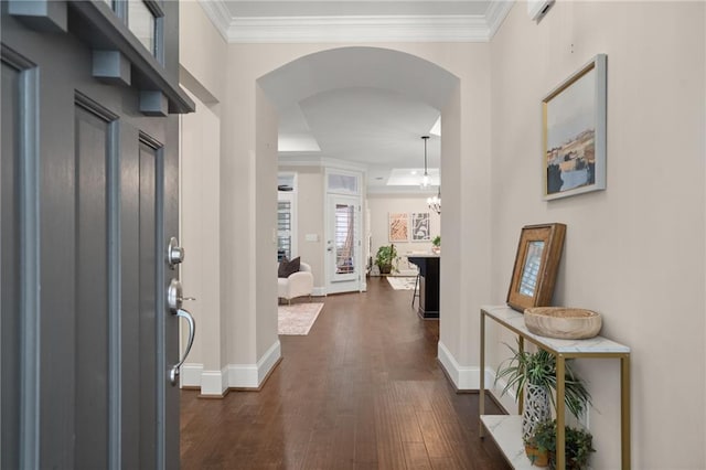 entryway with crown molding, dark wood-type flooring, and an inviting chandelier