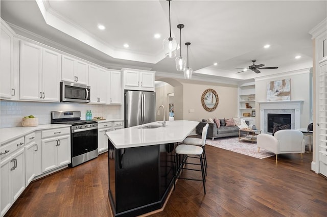 kitchen featuring white cabinets, stainless steel appliances, dark hardwood / wood-style floors, and an island with sink