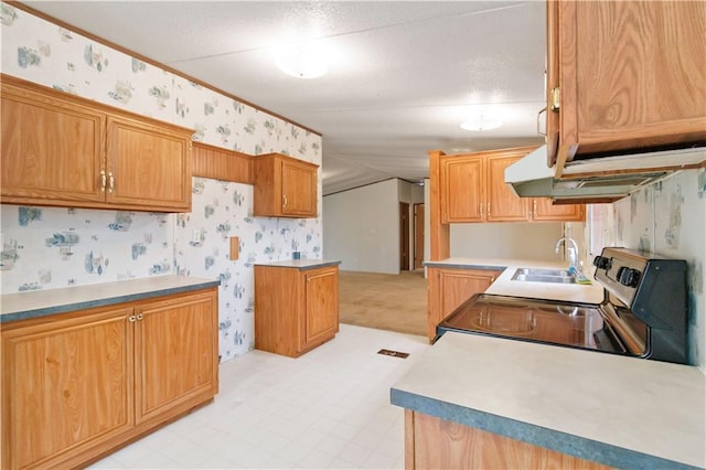 kitchen featuring a textured ceiling, electric range, a sink, light floors, and wallpapered walls