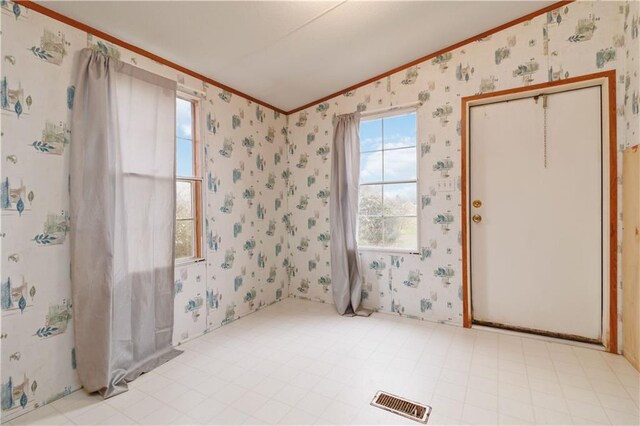 empty room with ornamental molding, visible vents, and wallpapered walls