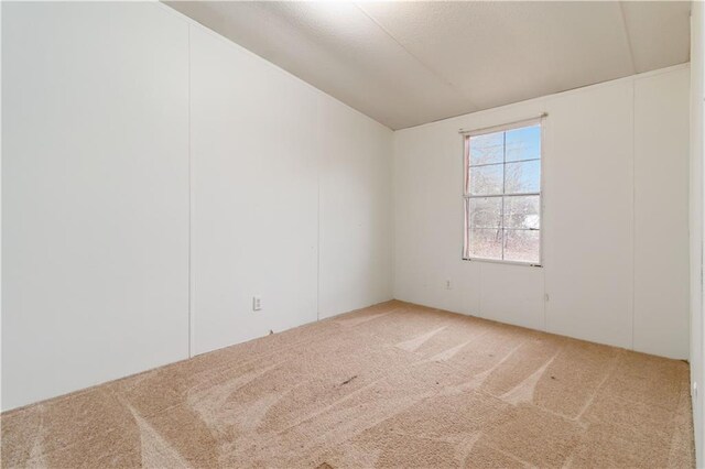 carpeted empty room with lofted ceiling