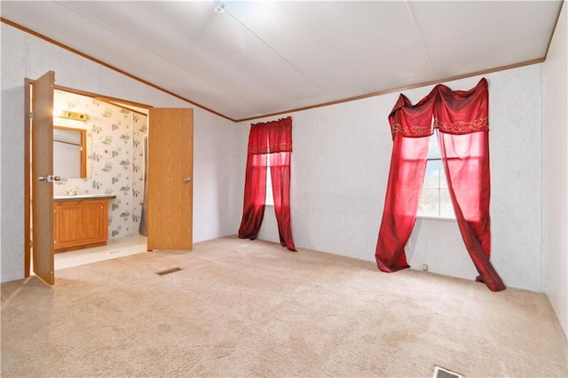 unfurnished room featuring vaulted ceiling, carpet flooring, and crown molding