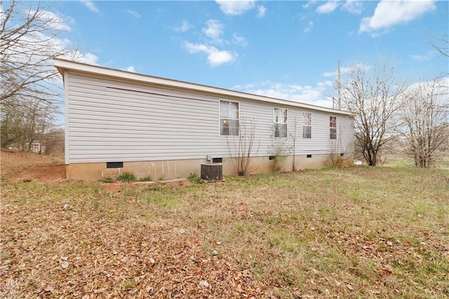 view of side of home with cooling unit, crawl space, and a yard