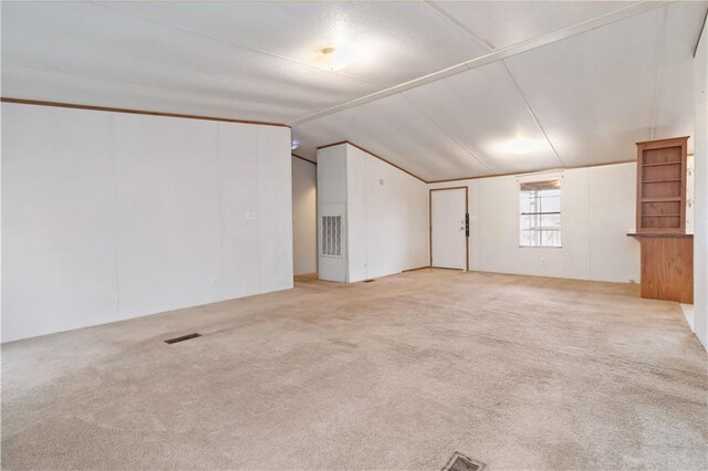 spare room featuring lofted ceiling, carpet flooring, and visible vents