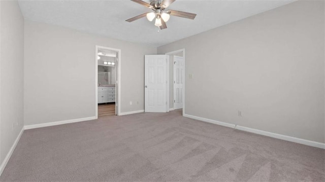 unfurnished bedroom with ensuite bath, carpet, baseboards, and ceiling fan