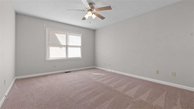 carpeted spare room with a ceiling fan, a textured ceiling, and baseboards