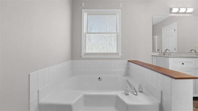 bathroom featuring a garden tub and vanity