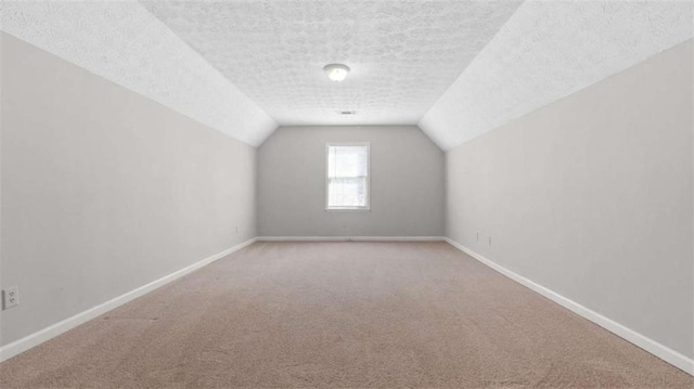 bonus room with a textured ceiling, vaulted ceiling, carpet, and baseboards