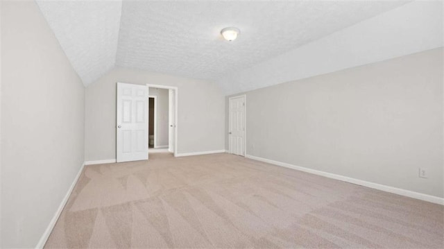 additional living space featuring carpet, baseboards, vaulted ceiling, and a textured ceiling