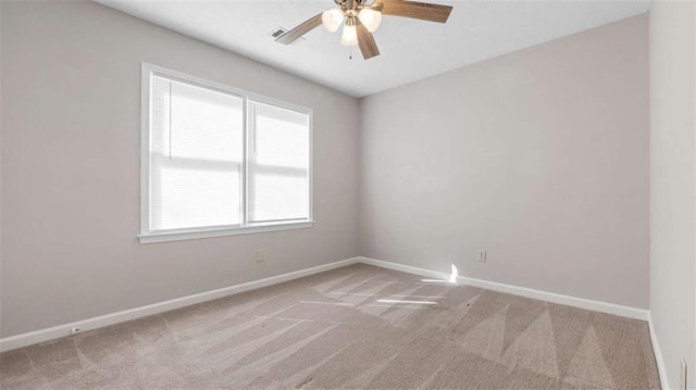 carpeted spare room featuring visible vents, ceiling fan, and baseboards