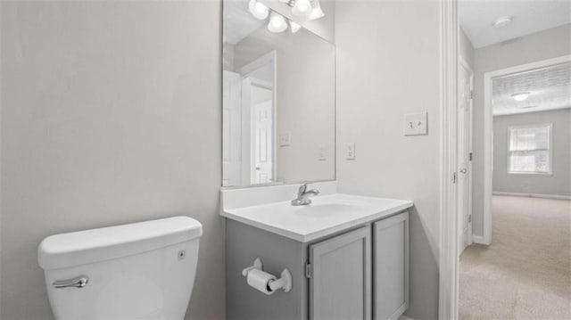 half bathroom featuring toilet, baseboards, and vanity