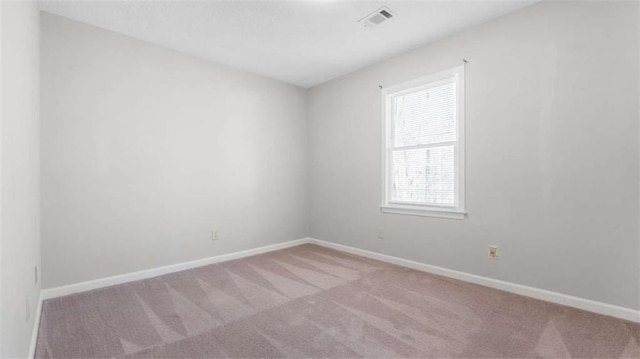 carpeted spare room featuring visible vents and baseboards