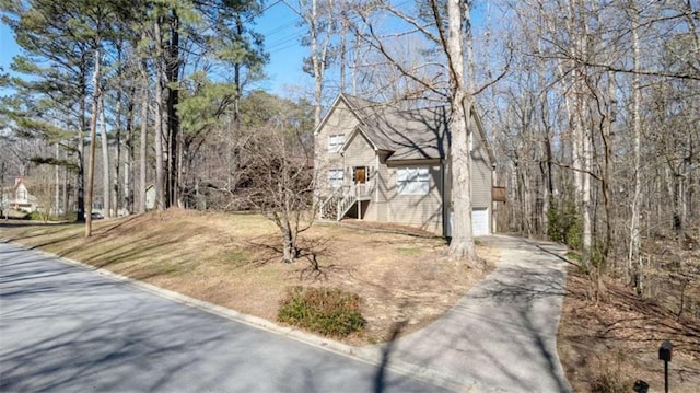 view of yard with a garage, stairs, and concrete driveway