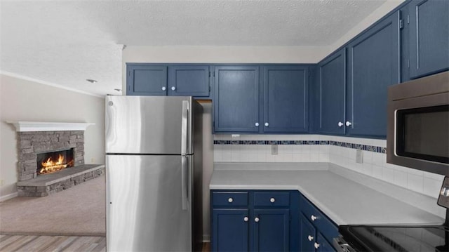 kitchen featuring stainless steel appliances, light countertops, blue cabinets, and decorative backsplash