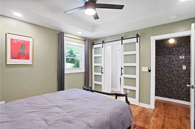 1202 Key Rd SE, Atlanta, GA 30316 - bedroom with a barn door, wood finished floors, baseboards, a tray ceiling, and recessed lighting
