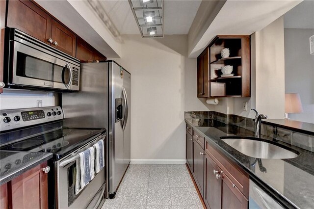 kitchen featuring dark stone counters, sink, and stainless steel appliances