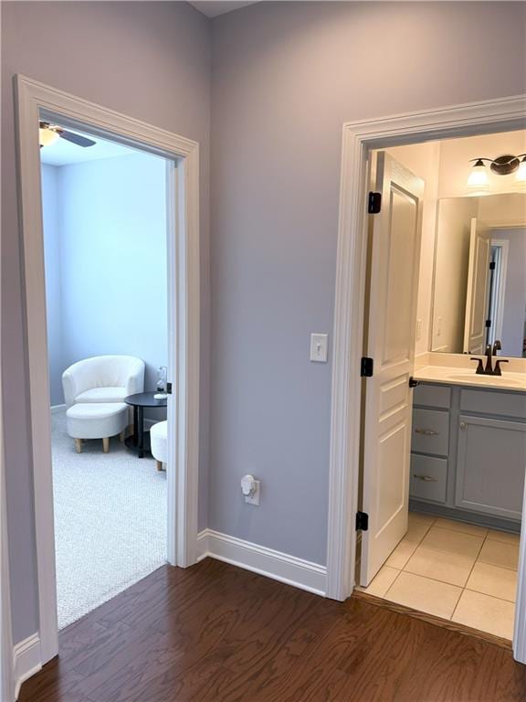 hall featuring a sink, baseboards, and light wood-style floors