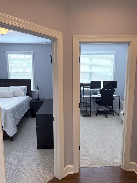 carpeted bedroom featuring baseboards and wood finished floors