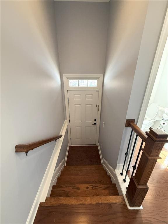 stairs with baseboards, a high ceiling, and wood finished floors