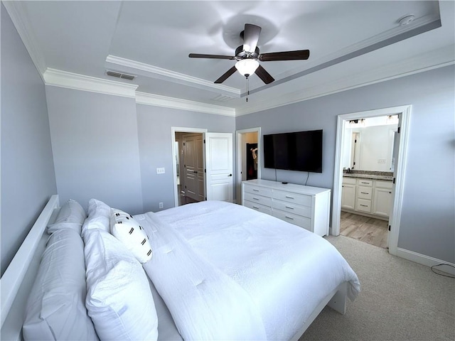bedroom with a tray ceiling, crown molding, ensuite bathroom, and visible vents