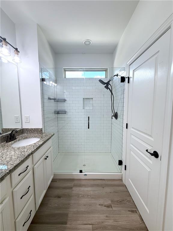 bathroom with a stall shower, vanity, and wood finished floors