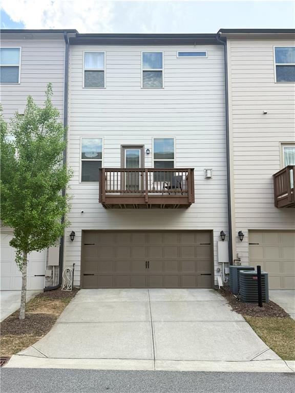 rear view of property with central AC unit, concrete driveway, and a garage