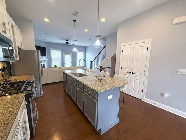 kitchen featuring a kitchen bar, a sink, stainless steel appliances, visible vents, and ceiling fan
